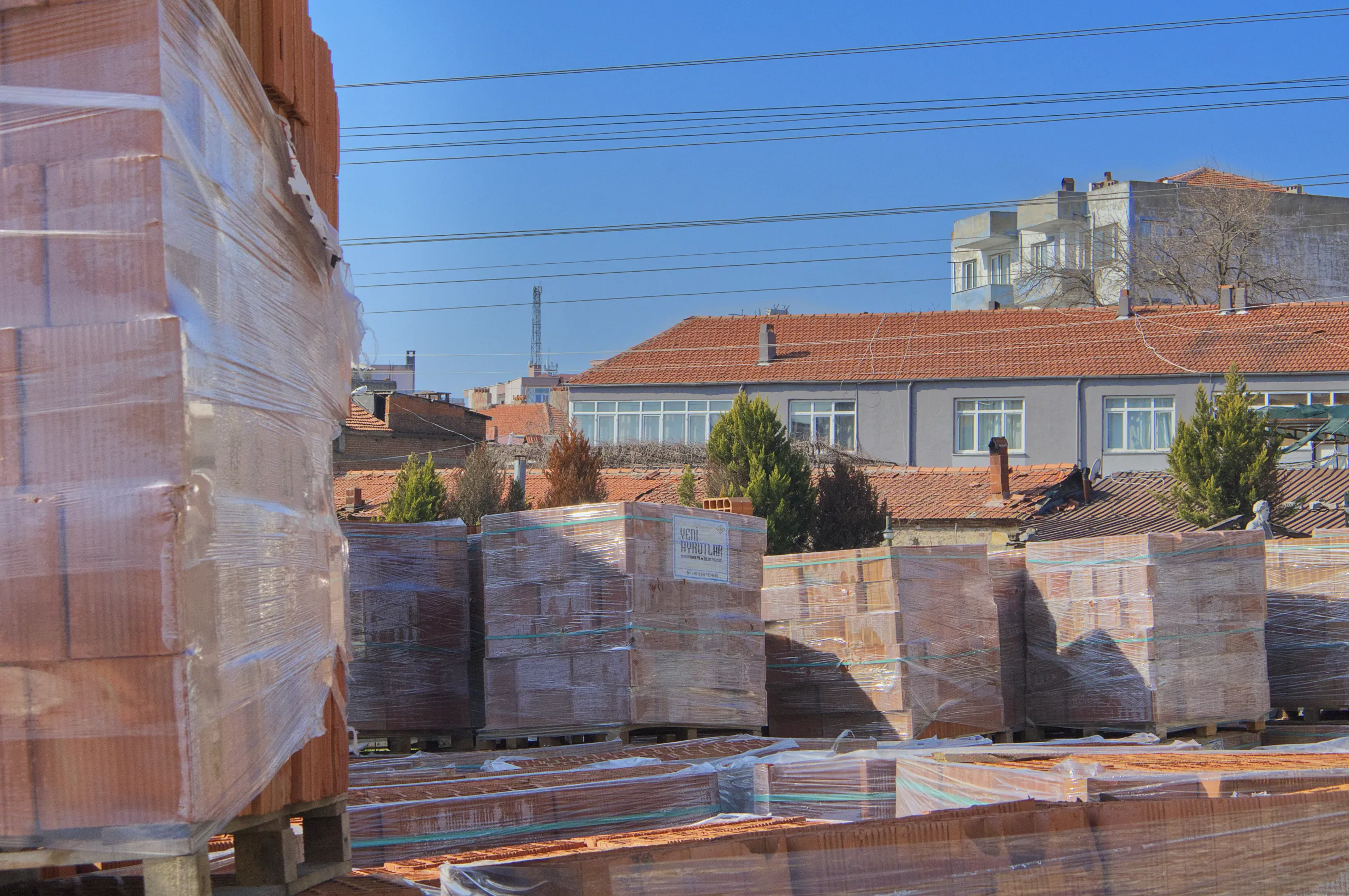 Beton kolonları ve tuğla duvarları görülen, üst kat kalıp ve demir donatıları hazırlanan çok katlı bina inşaatı.