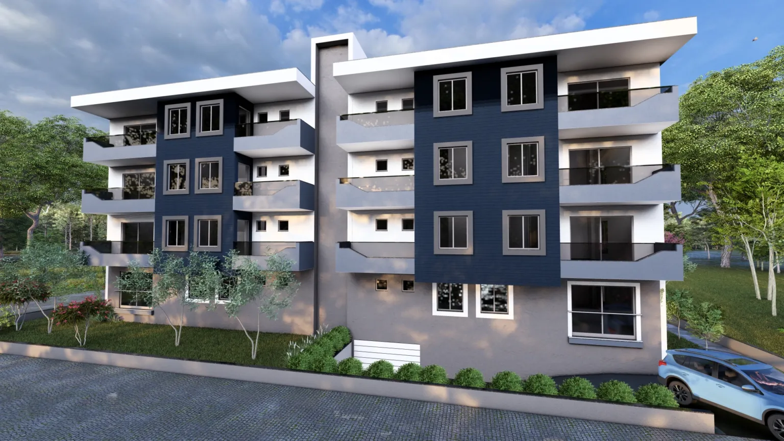 Angled front view of a contemporary residential building with white and navy façades, glass-fronted balconies, landscaped gardens, and a driveway.