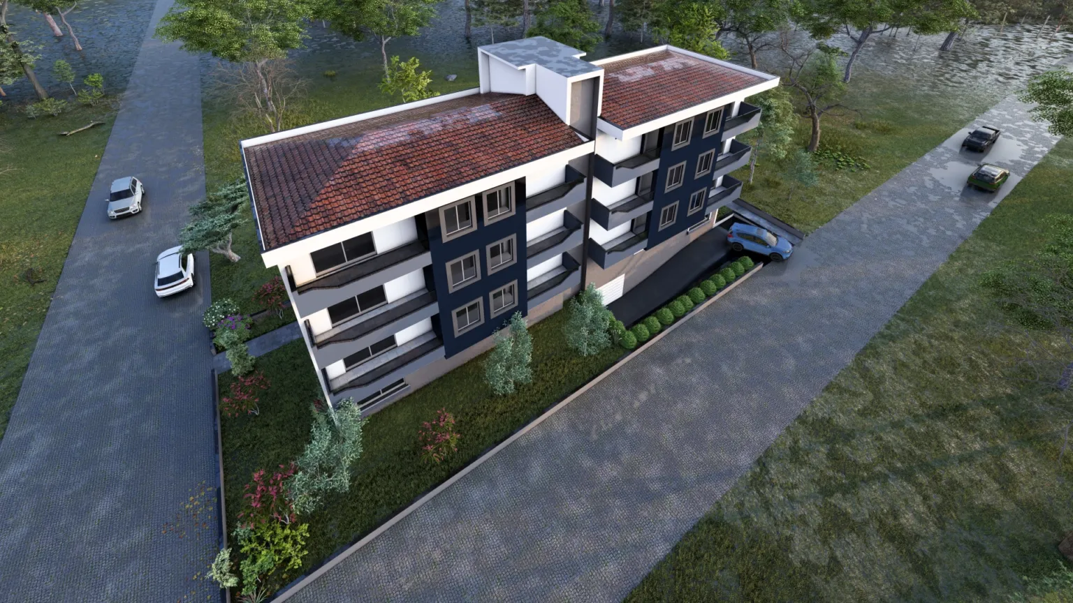 Aerial perspective of a modern apartment building showing its red tiled roofs, navy façade sections, balconies, landscaped grounds, and surrounding roads.