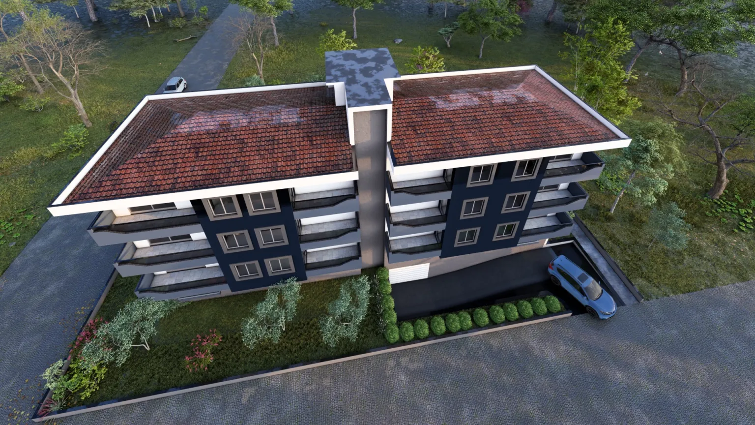 High aerial view of a contemporary apartment building with two red tiled roof sections, balconies, landscaped gardens, and a vehicle driveway.