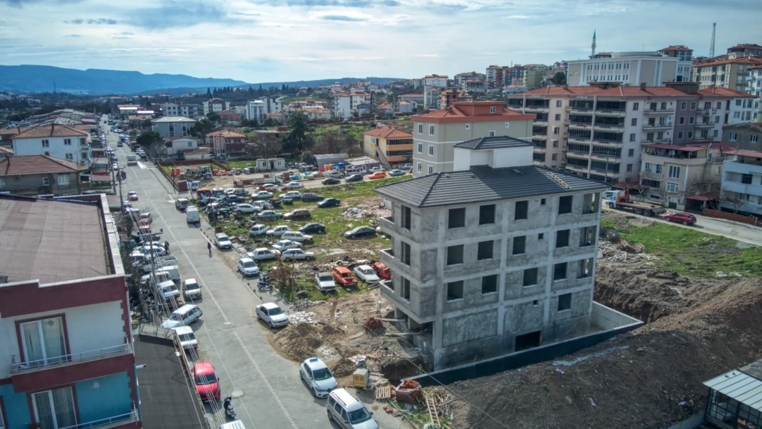 Small House projesinin üstten çekilmiş inşaat görünümü; çevresinde araçlar, şantiye alanı, apartmanlar ve uzakta tepeler görülüyor.