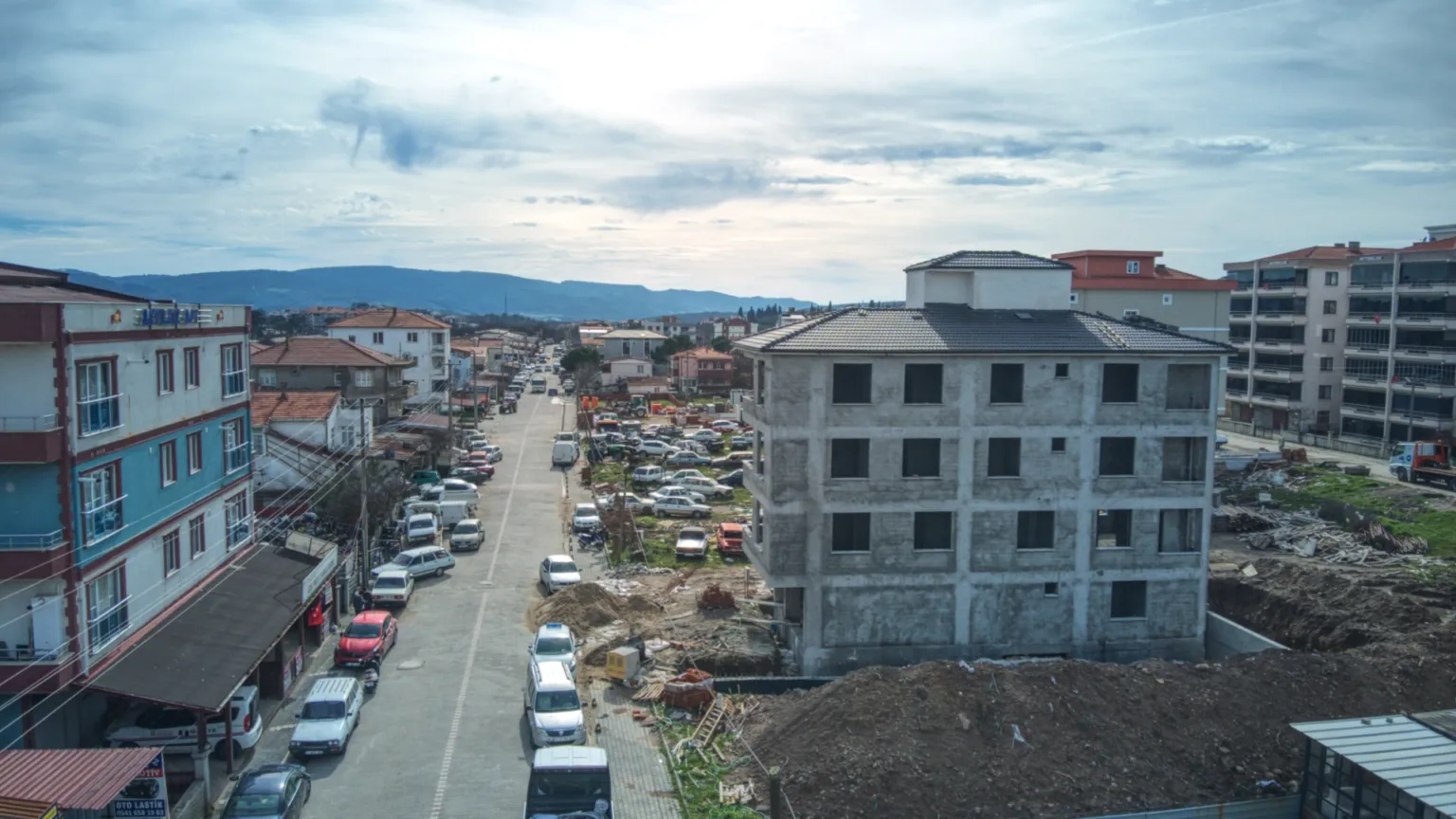 Small House projesinin betonarme yapısını, hareketli caddeyi, çevredeki apartmanları ve arka plandaki tepeleri gösteren panoramik görünüm.