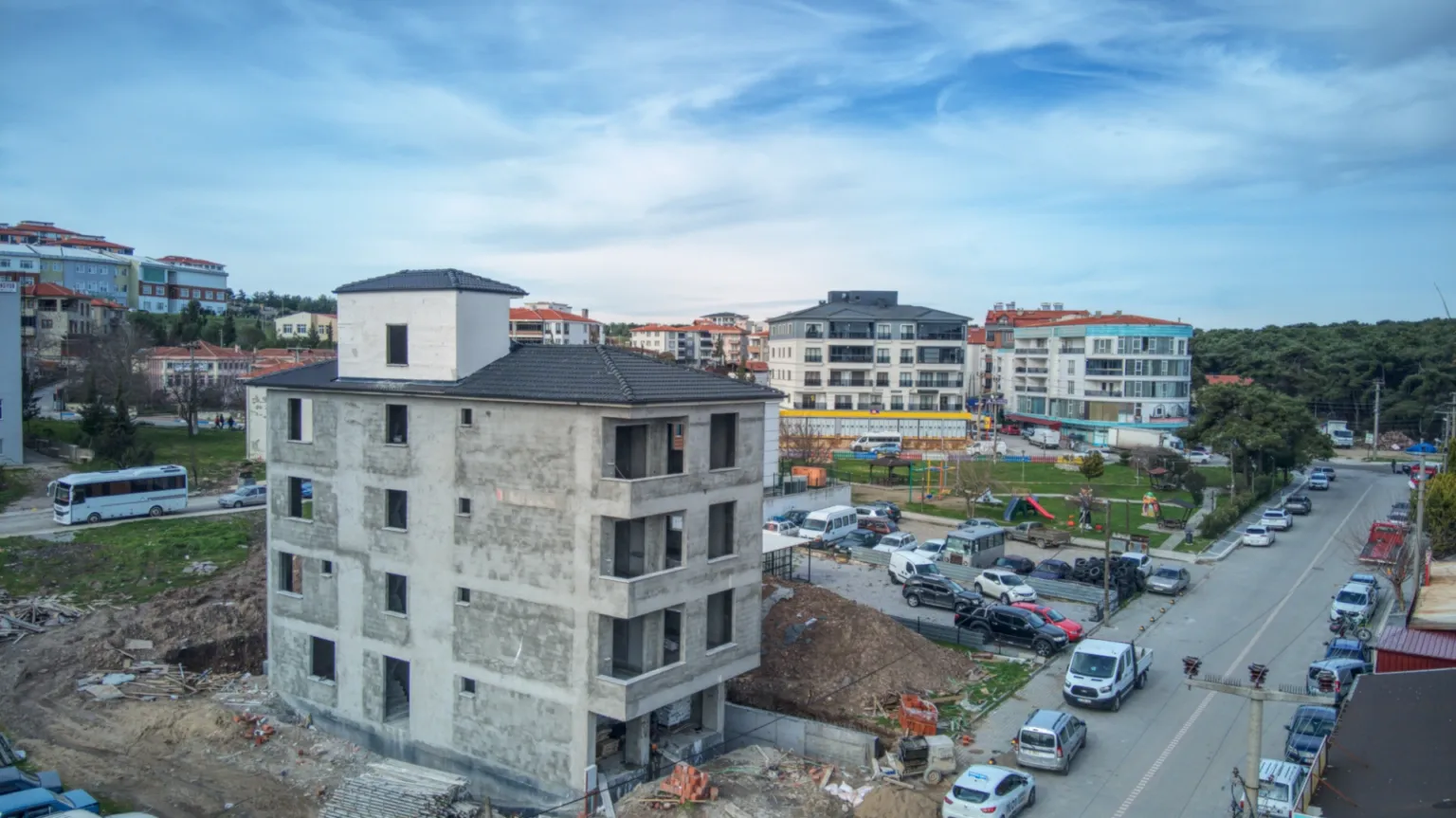 Small House projesinin çatılı kaba inşaatını ve çevresindeki park, caddeler, araçlar ile çok katlı yapıları gösteren havadan görünüm.