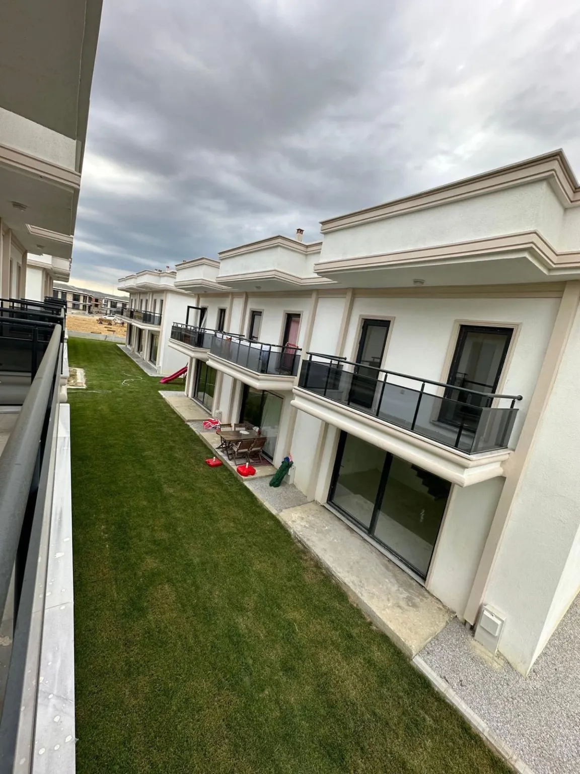 Upper-floor view of the balconied homes and shared lawn at Gelibolu Beyaz Kent.