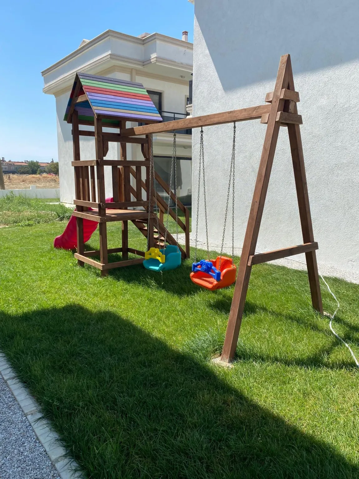 Gelibolu Beyaz Kent Sitesi’nin çim bahçesindeki kaydıraklı ve salıncaklı ahşap çocuk oyun alanı.