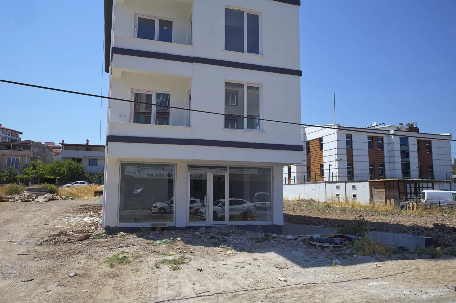 Slightly angled façade view of the Small House project showing the glazed ground floor, upper-level windows and balconies.