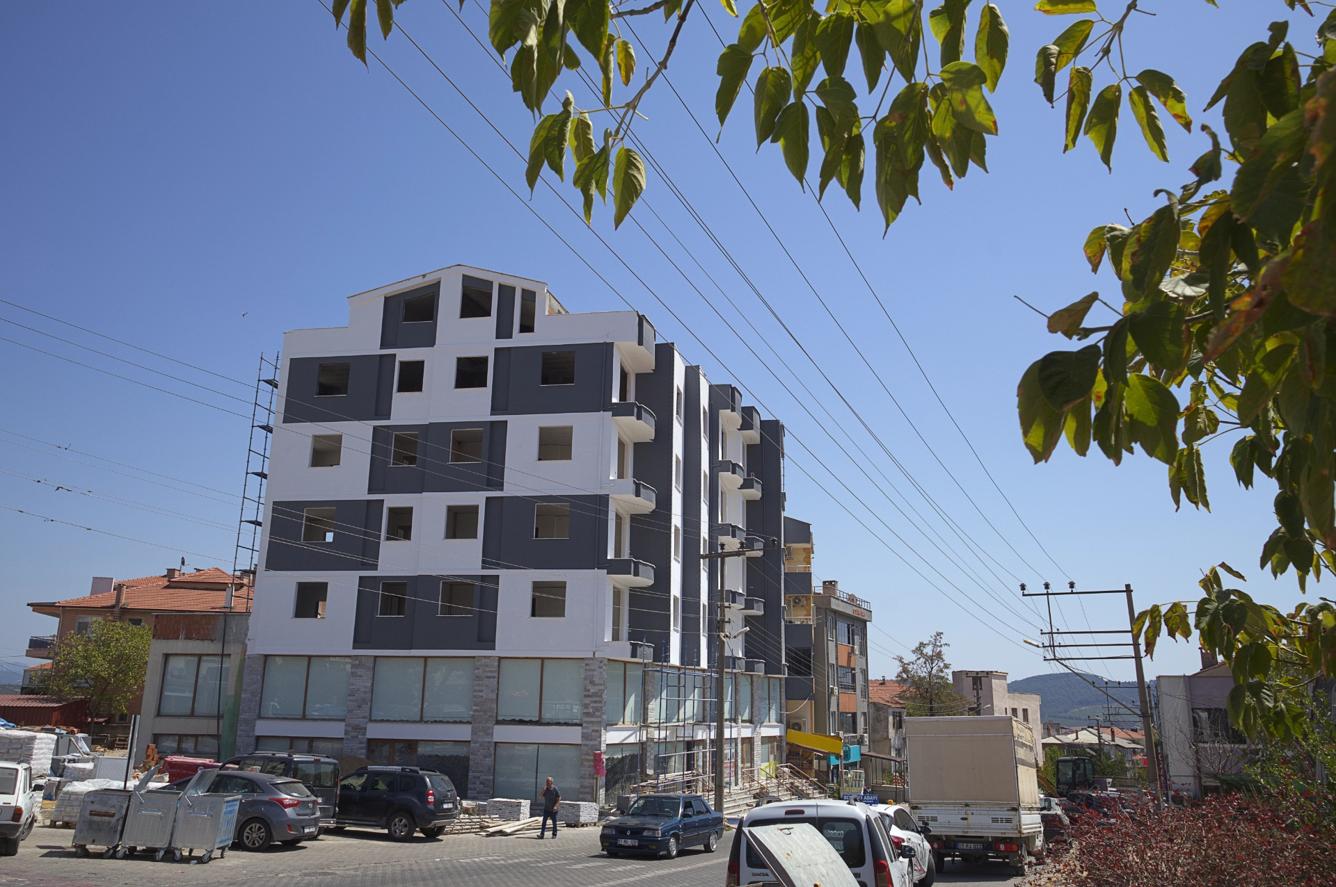 Şehir içinde, yapımı devam eden gri ve beyaz cepheli çok katlı modern bina.