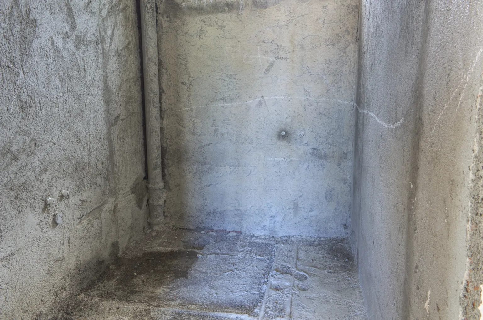 Small House projesinde kaba sıvalı duvarları, tesisat bağlantıları ve ham zemini bulunan yapım aşamasındaki küçük ıslak hacim.