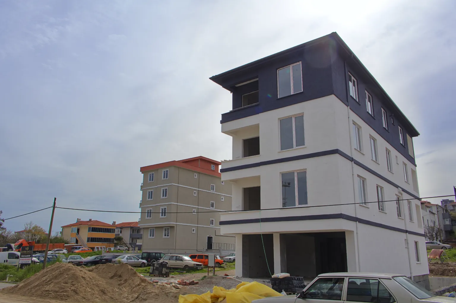 Low-angle view of the Small House project under construction, featuring white and dark grey façades and newly installed windows.