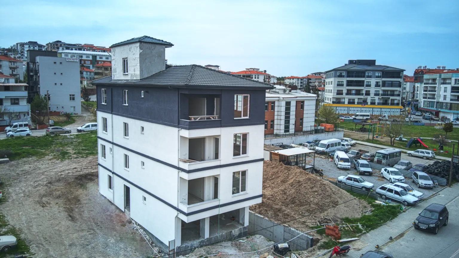 Small House projesinin balkonlu ön ve yan cephelerini, çatı detaylarını ve çevredeki kent dokusunu gösteren yüksek açı görünümü.