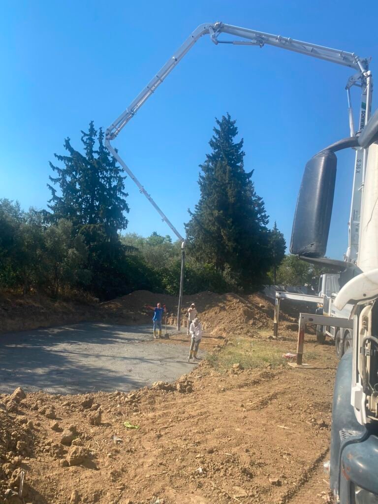 Ege İnci Konakları Evreşe şantiyesinde beton pompası ile temel alanında beton dökümü yapan işçiler.