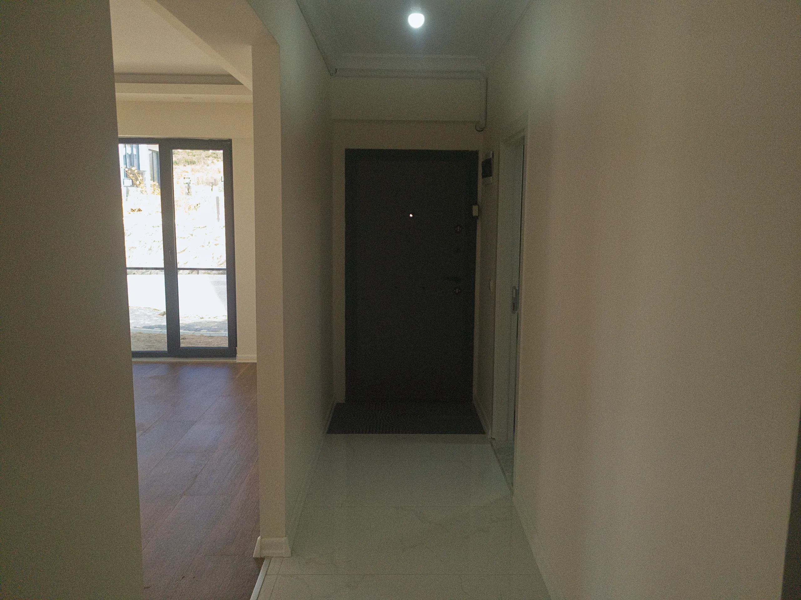 Konutun siyah giriş kapısı ile aydınlık yaşam alanına bağlanan sade ve modern antre bölümü.